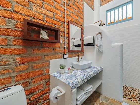 Baño con paredes de ladrillo y ducha en arco